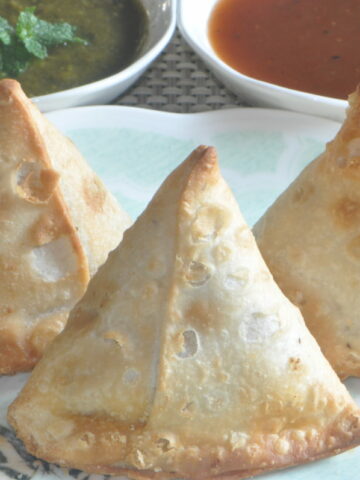 3 Air Fryer Samosa in a plate with chutneys in the side.