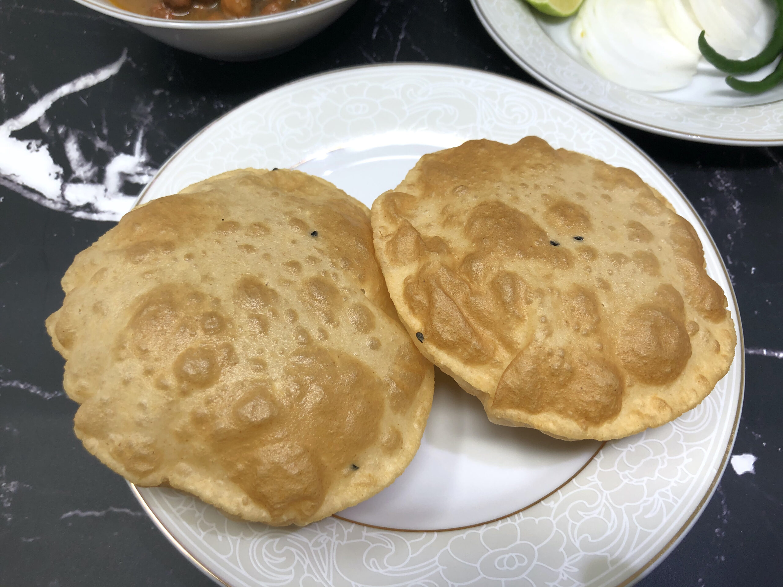 Two Deep fried puri or Indian puffed bread served in a plate.