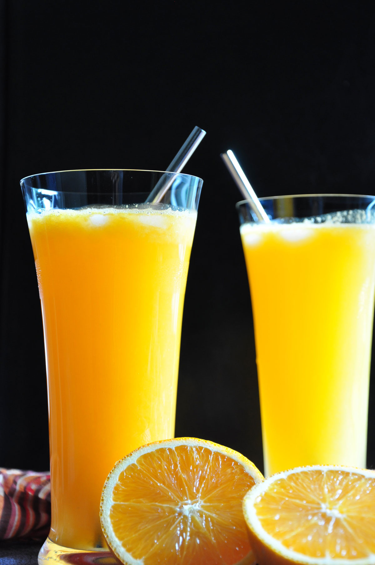 Orange Soda in two tall glass with a black background.