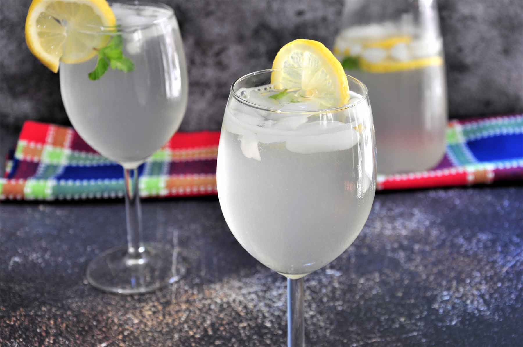 Lemonade in a wine glass garnished with lemon slice.