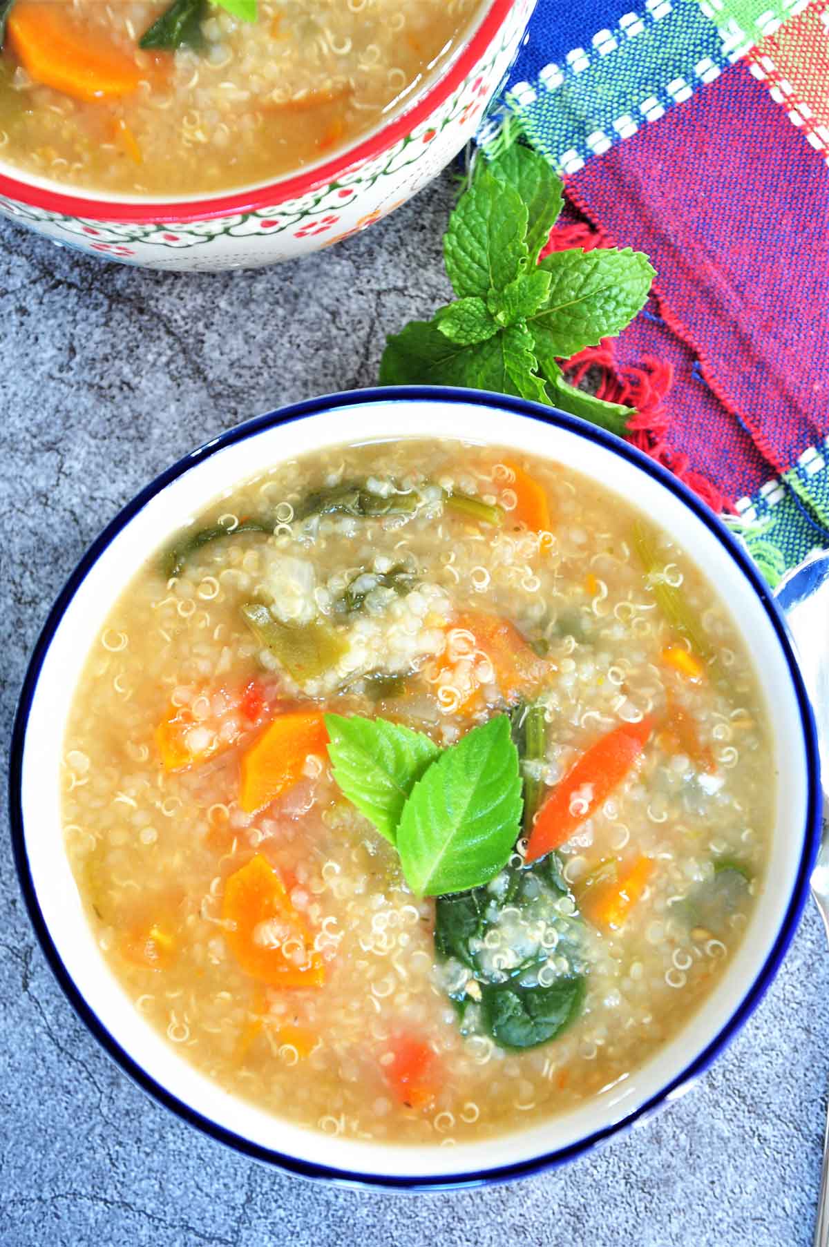 Quinoa Soup in a bowl garnished with basil leaves.