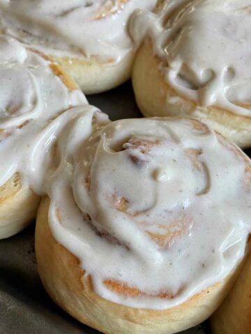 cloaeup image of cinnamon rolls with icing.