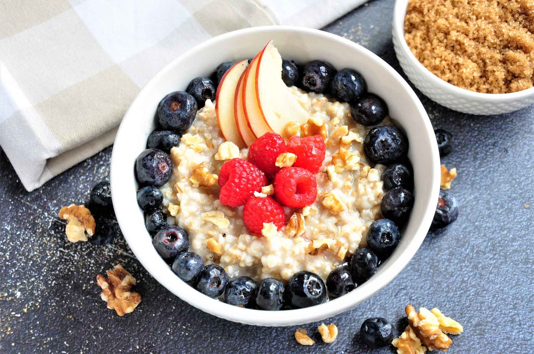 Instant pot cooked steel cut oats in bowl, served with berries and nuts on top.
