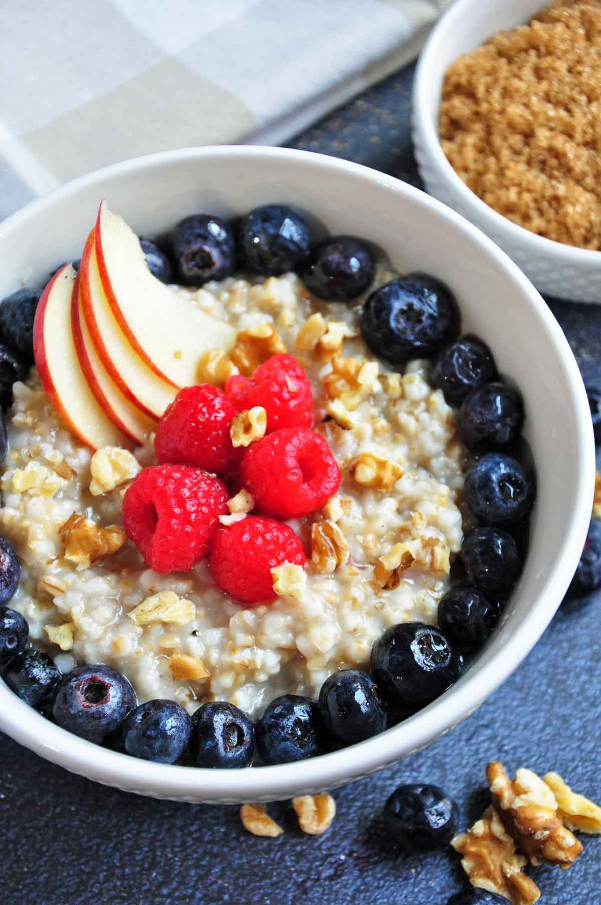 Instant pot cooked steel cut oats in bowl, served with berries and nuts on top.