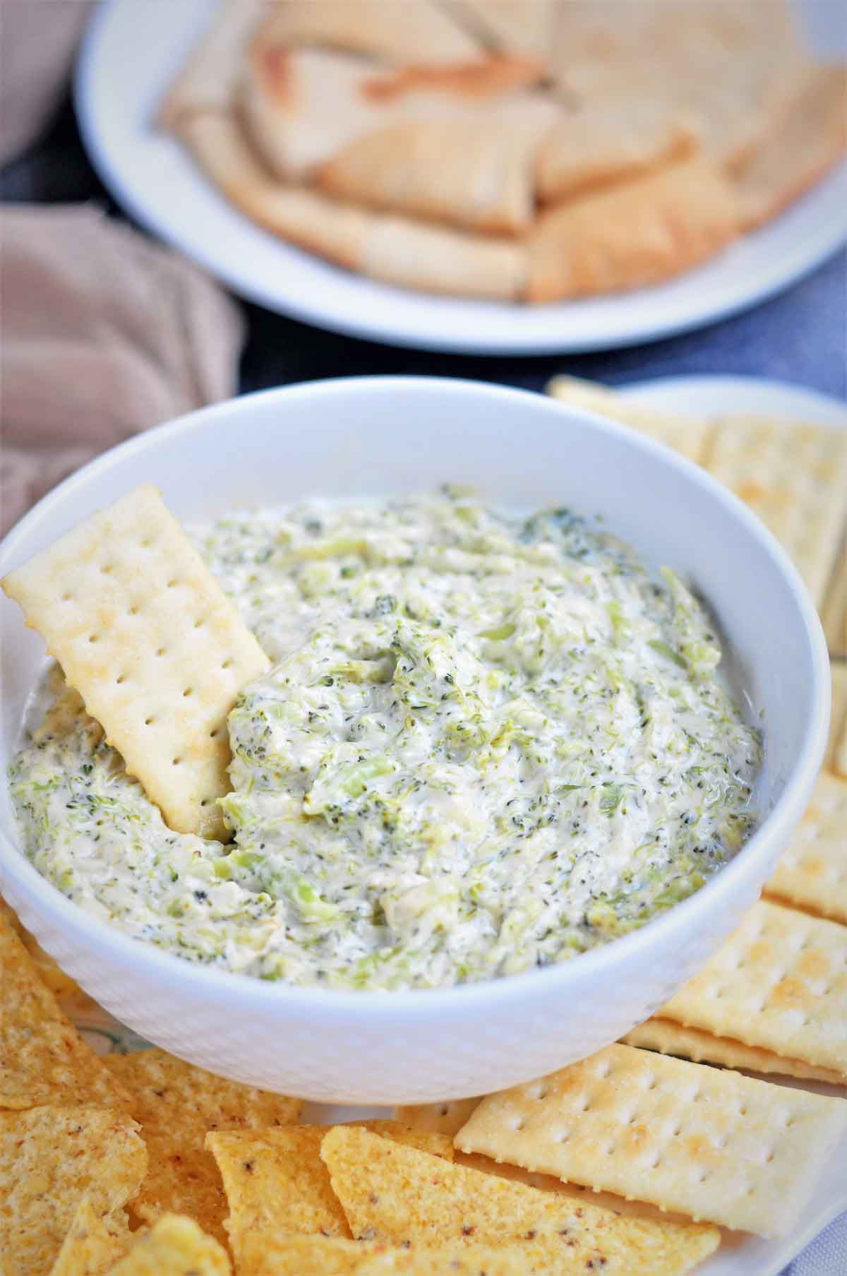 Broccoli cheese dip in a bowl served with crackers.