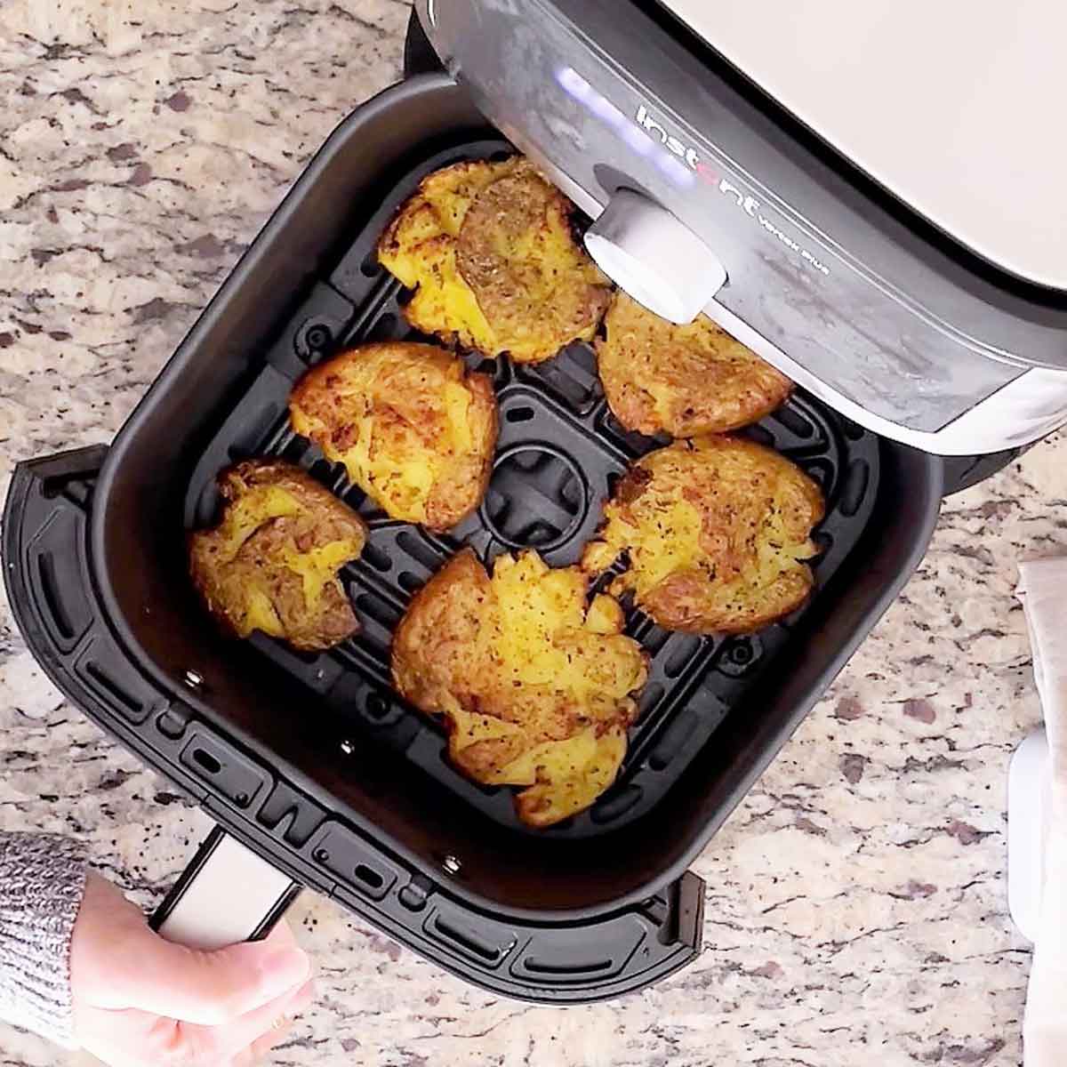 Roasted smashed potatoes in air fryer tub.