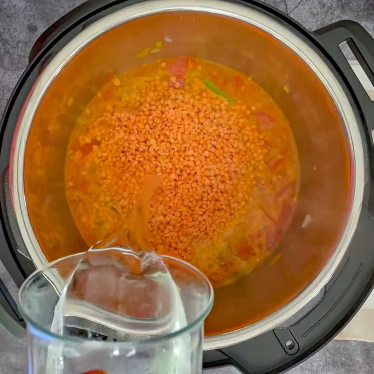 Adding water to Masoor dal.