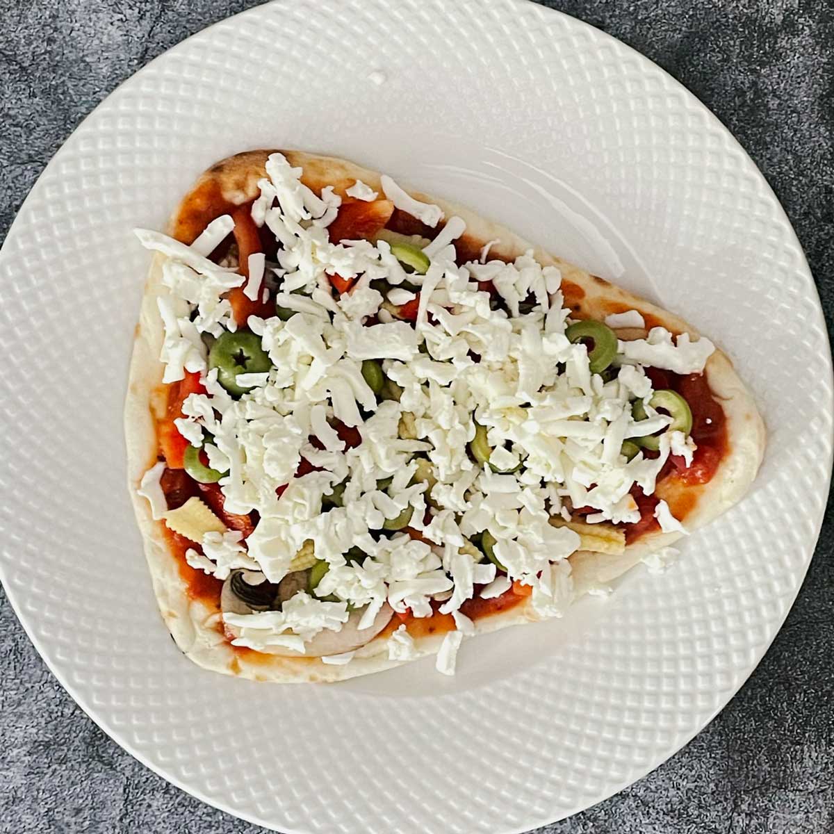 Naan pizza with veggies and cheese toppings.