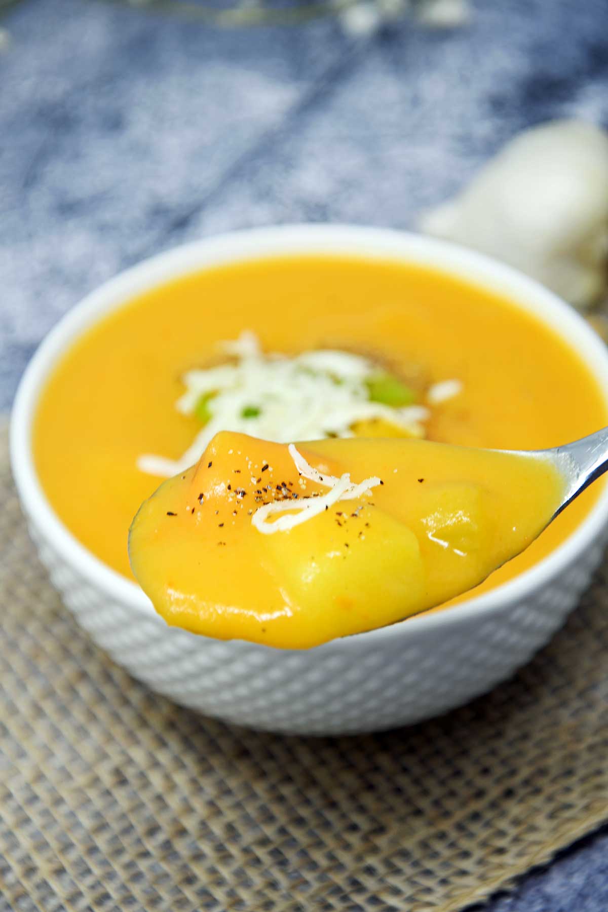 Potato soup in a serving bowl garnished with cheese and pepper.