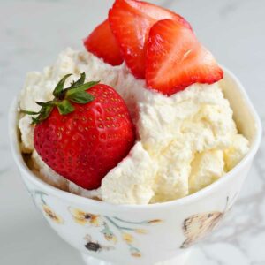 Whipped cream in a cup with strawberries.