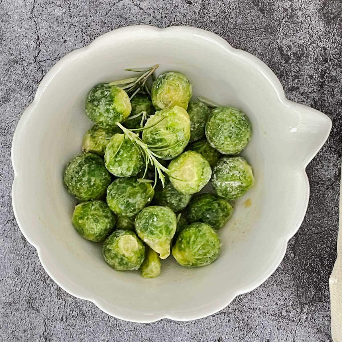 Air fryer frozen Brussels sprouts in mixing bowl.