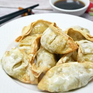 Air fryer potstickers in a plate with soy sauce on the side.