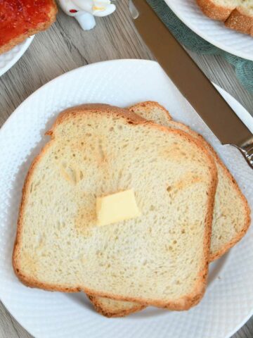 Air fryer toasted bread served on a plate with butter cube.