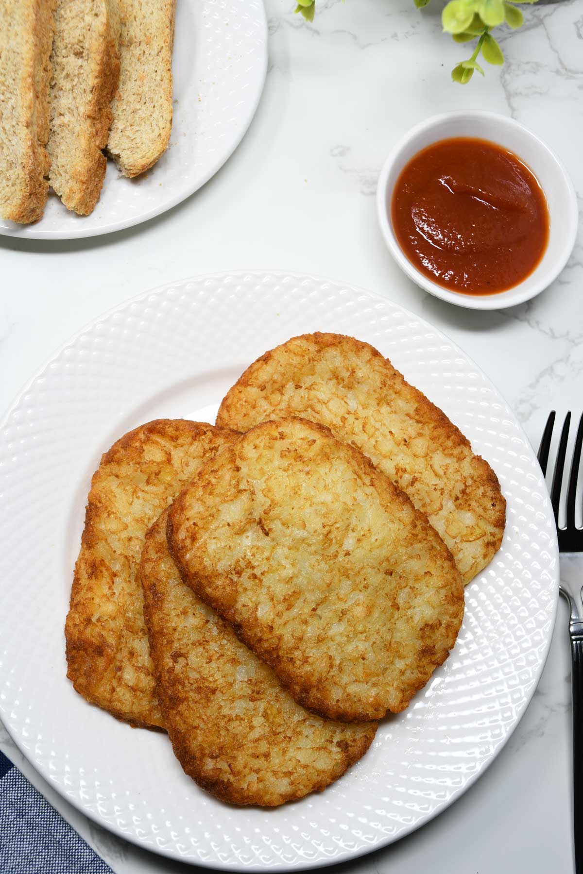 Air Fryer frozen hash browns served on a plate with ketchup.