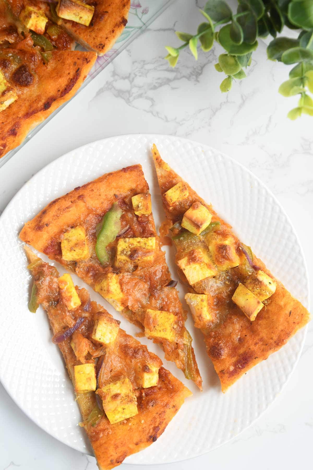 Paneer pizza slices in a plate.