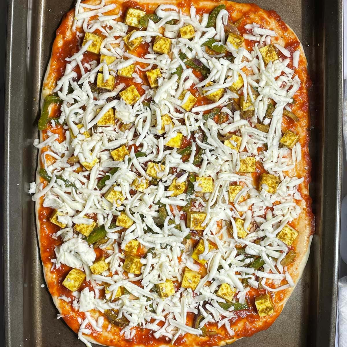 Paneer pizza in baking tray.