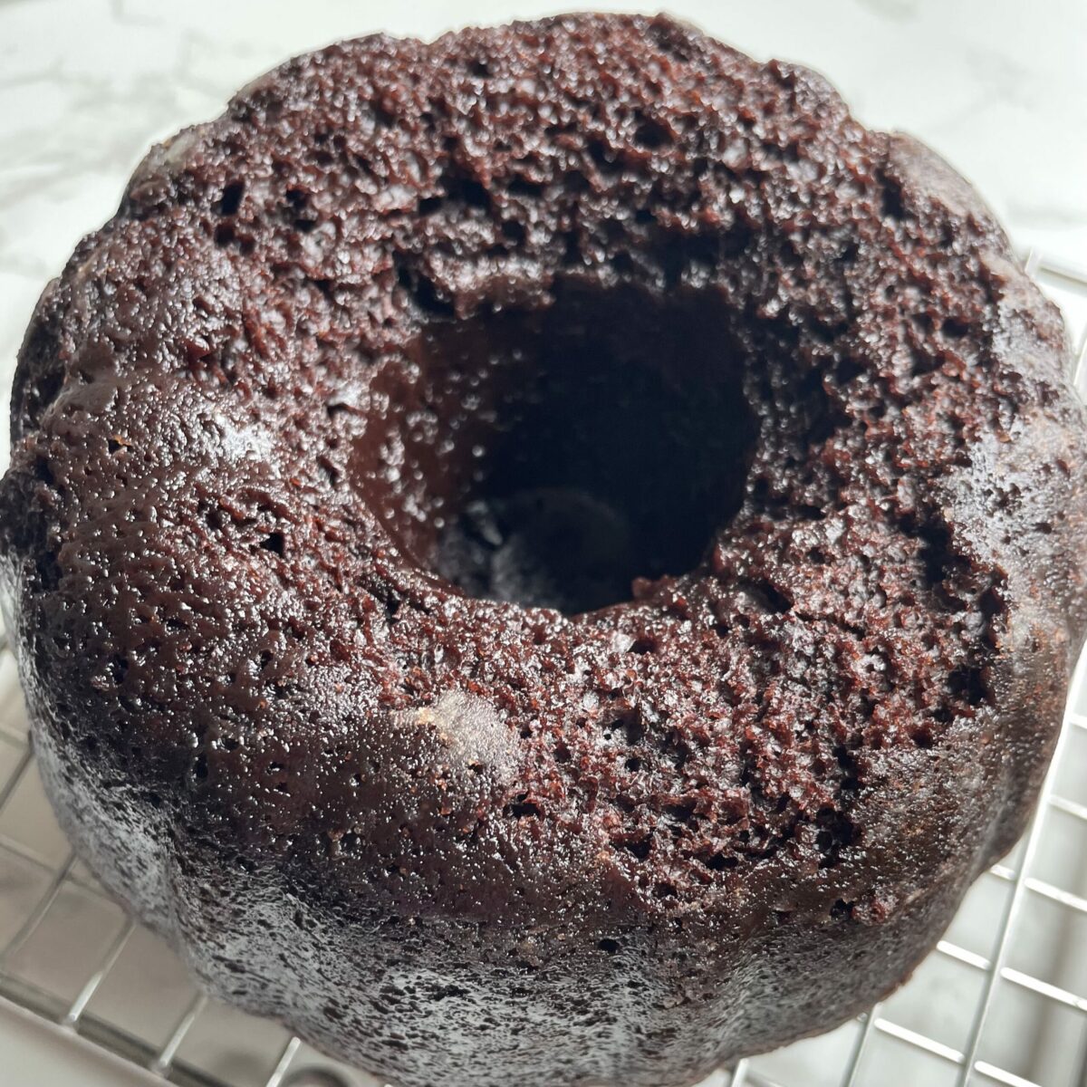 Bundt chocolate cake cooling down on a rack.