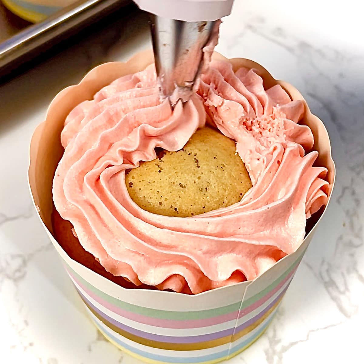 Applying frosting on cupcake.