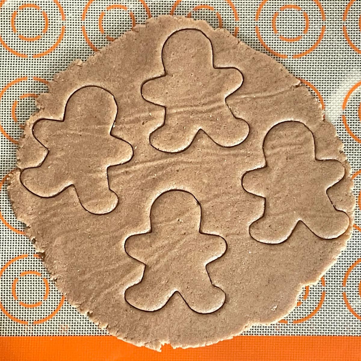 Gingerbread cookie shapes cut on rolled dough.