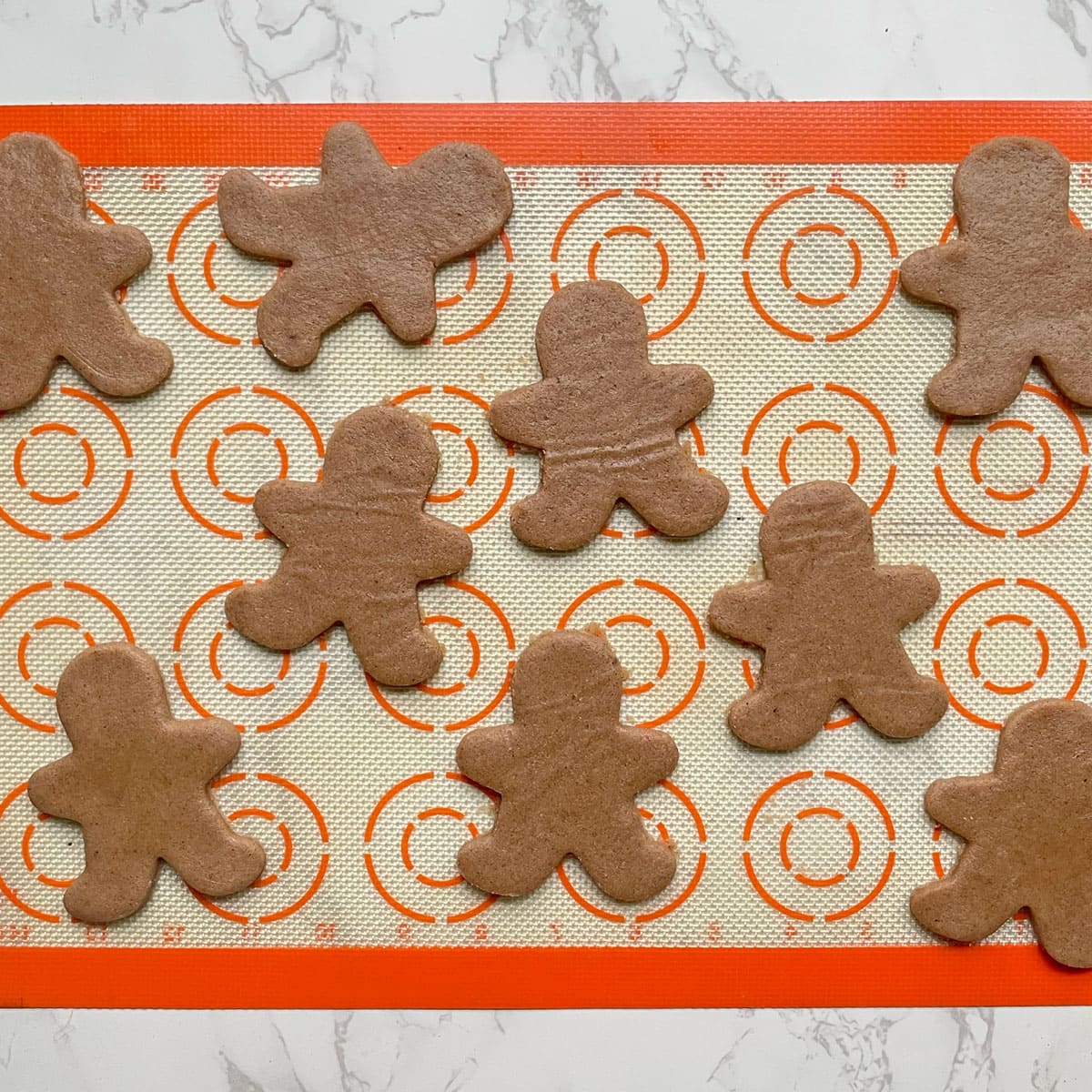 Gingerbread cookie cutouts on a mat.