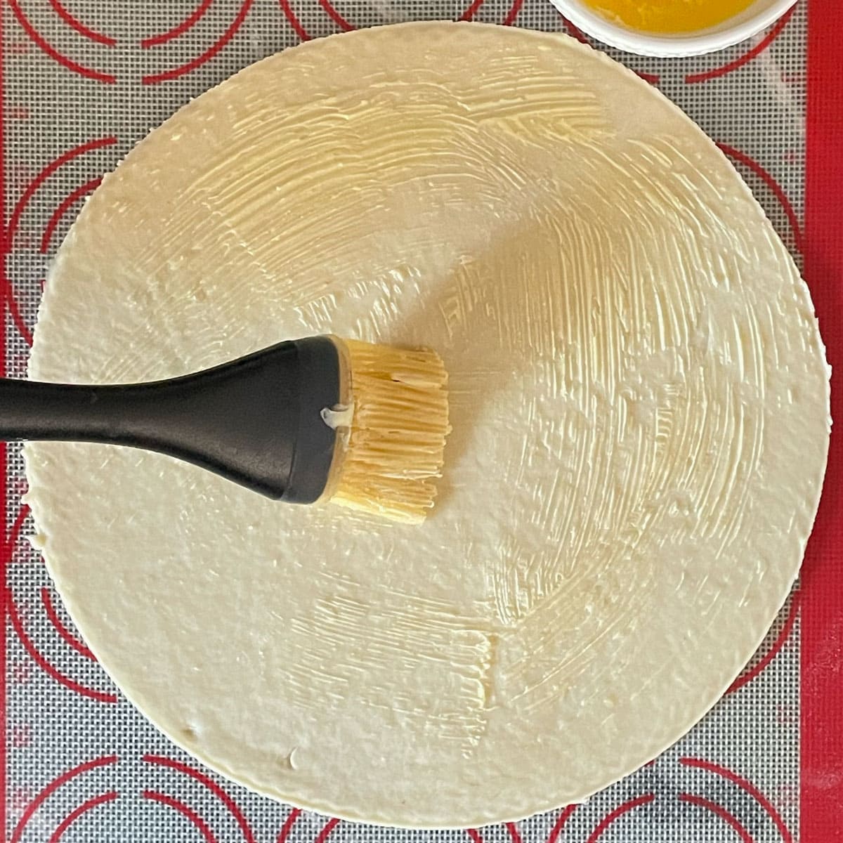 Applying butter to rolled dough.