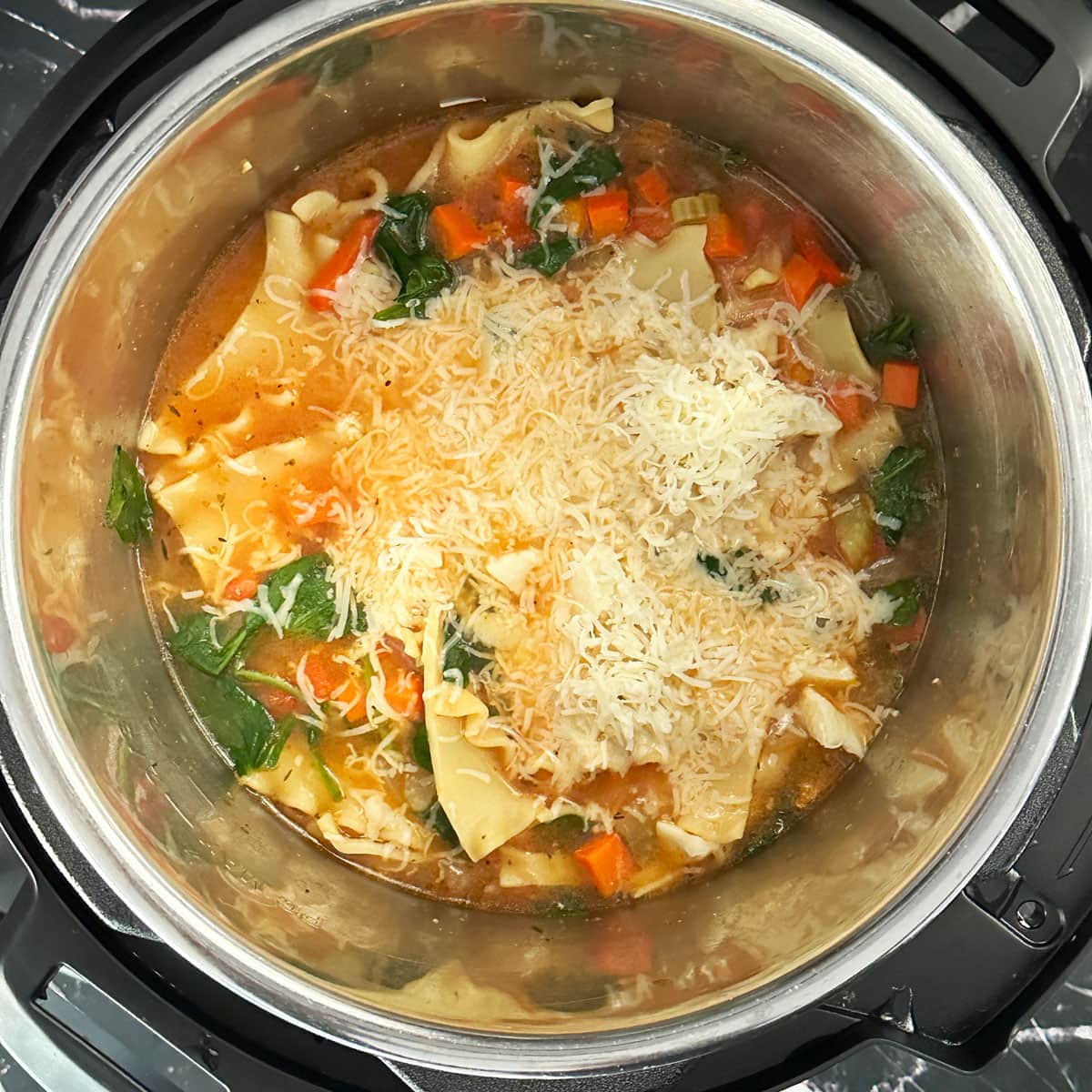 Cheese and spinach added to cooked Lasagna soup.