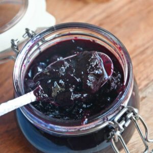 Blueberry jam in a jar with a spoon.